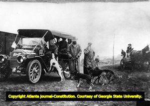Good Roads Tour automobiles greeted by bloodhounds during a pitstop, 1910