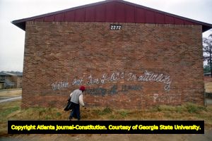 East Lake Meadows resident walks past graffiti sprayed on an apartment wall, 1991