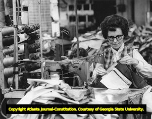 Textile worker Frances Popham stitches together men's slacks, 1972
