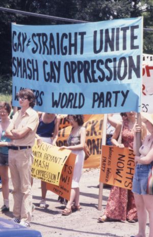 Workers World Party group marching in the Atlanta Pride parade with a sign reading "Gay and straight unite. Smash gay oppression," 1977