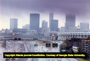 Skyline view of rain falling on Atlanta, Georgia, October 10, 1990. View over highway, with stadium on right and billboard ("Fly Delta") on left.