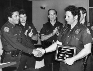 Police Captain Julian Ronald Spence accepting an award from police Chief Eldrin Bell, 1980
