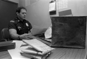 Police officer Julian Spence looks over the contents of a time capsule taken from Jerome Jones School, 1986