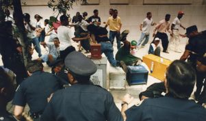Demonstrators are pushed back over newspaper stands during a confrontation with police during the Rodney King demonstration, 1992