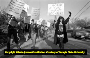 Demonstrator "Lady Claire" with a sign reading "Honk if you want hookers" during a clash between anti and pro sex worker demonstration, 1985