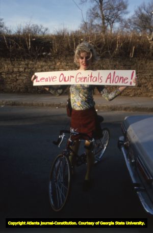 Demonstrator holding a sign reading "Leave our genitals alone!" during a pro and anti-sex worker demonstration, 1985
