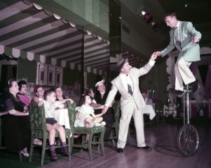 Comedia Jimmie Costello and unicyclist Larry Lynn entertain guests at the Henry Grady Hotel's Paradise Room, 1954