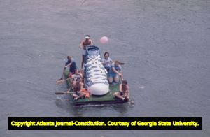 Ramblin' Raft Race down the Chattahoochee River, Atlanta, Georgia, May 21, 1977. Six-man raft with enormous sneaker (athletic shoe) in the middle.