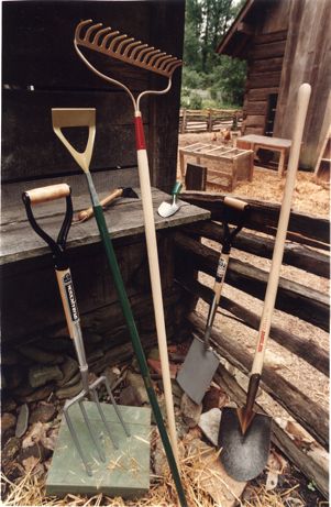 Shovels, pitchfork, rake, and garden tools against a barn, rural Georgia, 1990s?