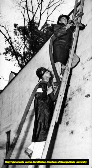 Firemen at practice, climbing ladder with water hose, Atlanta, 1942.