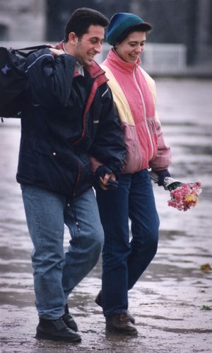 Muslim couple walking down the street holding hands, the woman holding fresh flowers, South Asia or Middle East, photograph by Jean Shifrin, 1992.