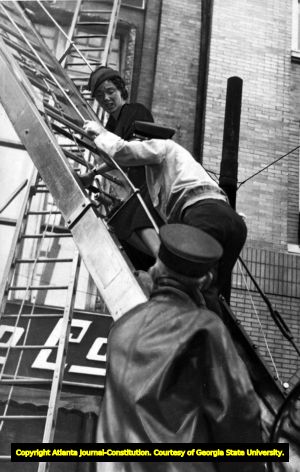 Fireman helping a woman caught in the Cable Piano Company fire to climb down a ladder, Atlanta, November 19, 1936.