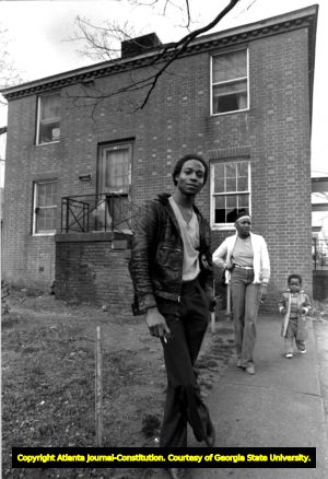 African American man, woman, and child standing outside a derelict apartment (?) building, Atlanta, Georgia, February 17, 1982.