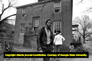 African American man, woman, and child standing outside a derelict apartment (?) building, Atlanta, Georgia, February 17, 1982.
