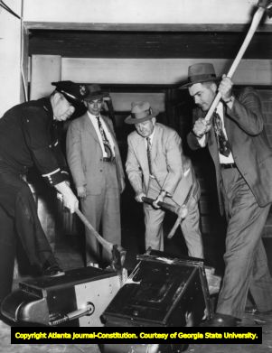 Fulton County war on slot machines during 1954; here, three men use axes to hack apart slot machines, Fulton County, Georgia, November 12, 1954.