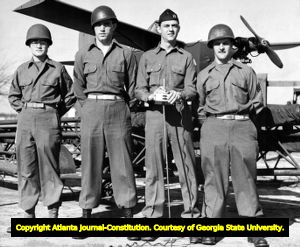 Four soldiers standing in front of small pilotless, remote-control plane at For Benning, Georgia. Soldier holding the radio-control is Captain Richard M. Horton. 1940s?