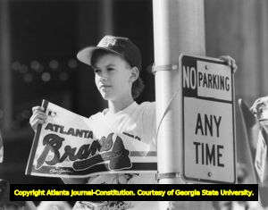 Child (Josh Erwin) on street lamp pole, holding Atlanta Braves pennant at parade, Atlanta, Georgia, October 10, 1991.