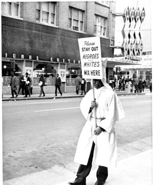 Ku Klux Klan member picketing outside of Leb's Restaurant, while African-American students demonstrate across the street, Atlanta, Georgia, February 3, 1964.