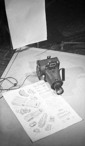 Camera with a Schneider lens posed next to an advertisement draft that reads, "The South's Greatest Sports Pictures," Atlanta Journal photography department, Atlanta, Georgia, 1949.