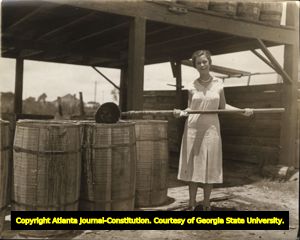 Nellie Mitchell, pouring pine resin into barrells at the J.L. Mobley turpentine still, Waycross, Georgia, 1930s?