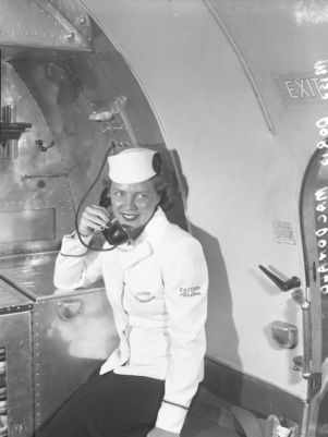 Eastern Airlines flight attendant Doris MacDonald on telephone in airplane, Atlanta, Georgia, late 1940s.