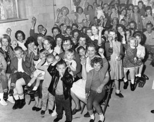 Textile workers and their families holding up fruit provided by the union, Fairburn, Georgia, March 1963.