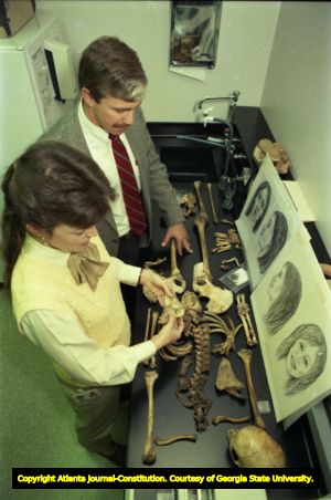GBI special agent and forensic anthropologist examine the remains of an unidentified woman (overhead view), 1988