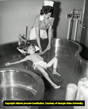 Physical therapist treating a child with pool therapy, circa 1940s