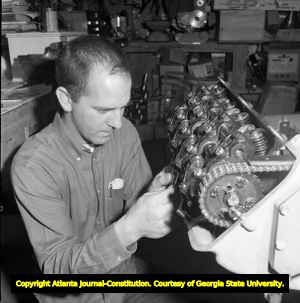 Pete Robinson in his garage working on an engine, 1966
