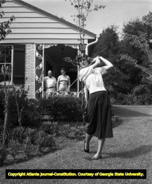 Mary Lena Faulk shows her golf swing with her parents watching, 1953