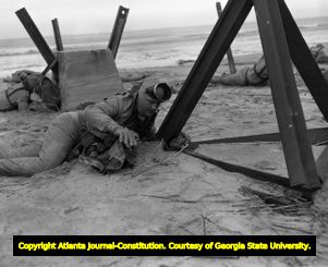 Frogmen practice setting explosives along a beach, 1956