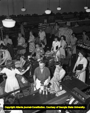 Grocery shoppers line up at the check-out lanes with their groceries, 1946