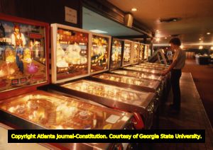 Row of pinball machines being played at a bowling alley, 1980