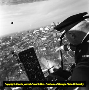 Atlanta Police Chief Herbert T. Jenkins pilots a helicopter over a city neighborhood, 1956