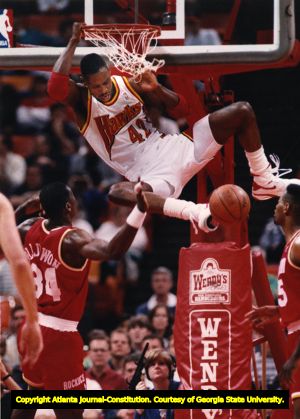 Hawk Kevin Willis hangs on the rim after dunking on Hakeem Olajuwon, 1993
