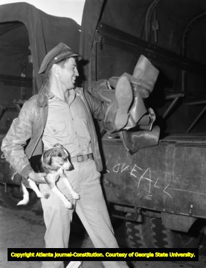 Airman returns a collection of military boots to a supply truck, 1945