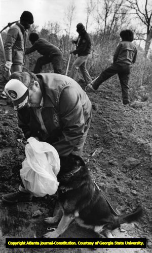 Volunteer searchers and a K-9 unit tries catching the scent of the missing children, 1980