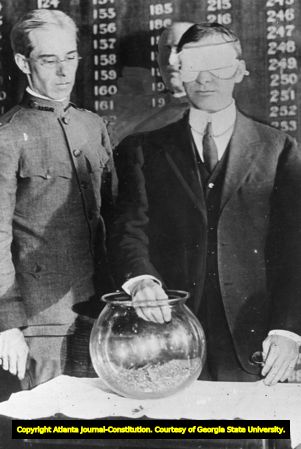 Blindfolded U.S. Secretary of War Newton D. Baker, drawing numbers from bowl in the 1917 draft lottery, Senate Office Building, Washington, D.C., July 21, 1917.