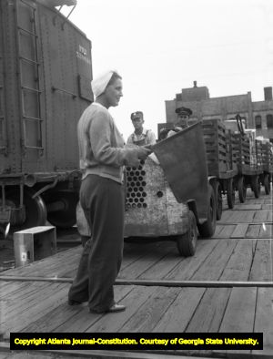 Woman flagman directs traffic within a railyard, 1945