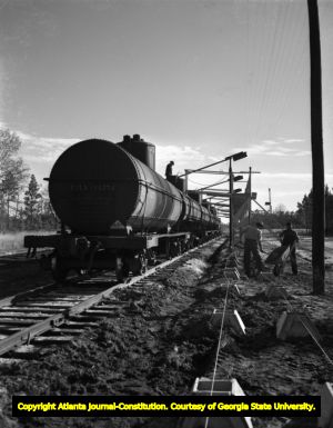 Workers ready a train car for a shipment of oil, 1952