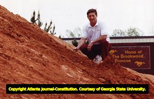Coach Dave Hunter sits at the construction site of the Brookwood High School football stadium, 1990