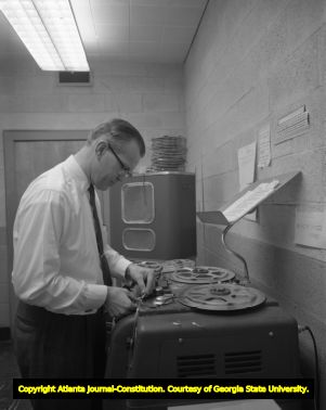 Religious television station worker splicing film reels together, 1961