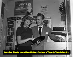 Record store couple demo a vinyl record, 1951