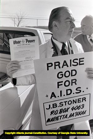 White supremacist holds up sign "Praise God for A.I.D.S" at a march, 1988