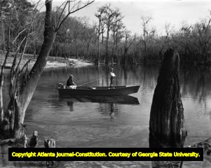 Father and son fishing on a swampy creek, circa 1940s