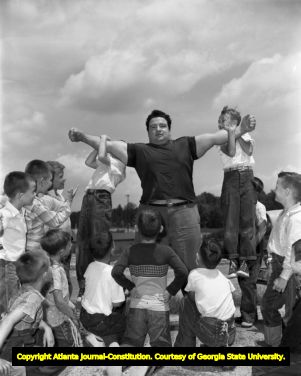 Weightlifter Paul Anderson showing off his strength to a group of boys, 1955