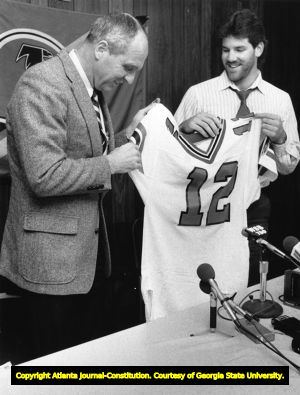 Newly signed Chris Miller holds up his Falcons' jersey during a press conference, 1987