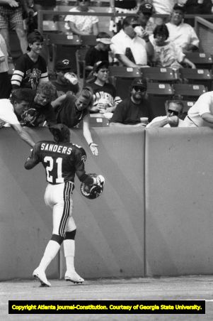 Falcons' player Deion Sanders shakes hands with fans in the stands, 1990