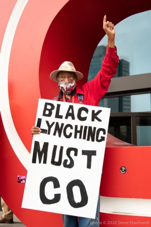 A protester holds up a sign reading 'Black Lynching Must Go'