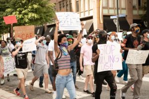 A protester marches through the street holding a sign reading 'I Can't Breathe'